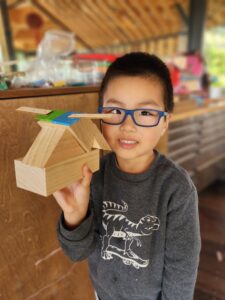 Preschool child showing their wooden carpentry construction at childcare Kakapo Creek
