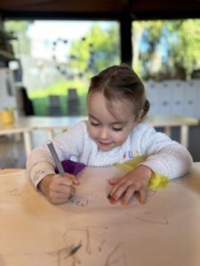 preschool child drawing with felt tip on brown paper